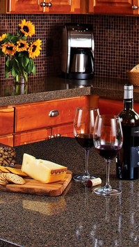 Butelka wina, kieliszki i ser na blacie w kuchni