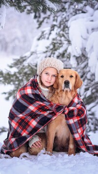 Dziewczynka i golden retriever pod kocem na śniegu