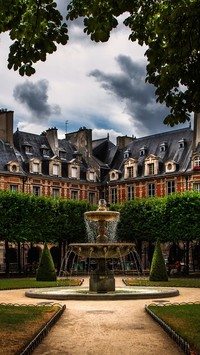 Park z fontanną otoczony domami w Paryżu