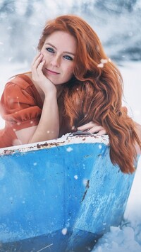 Rudowłosa dziewczyna w łódce na śniegu