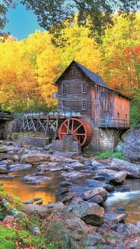 Stary drewniany młyn nad rzeką jesienią