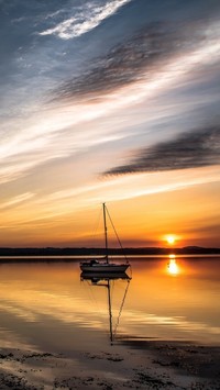 Żaglówka na jeziorze na tle zachodu słońca