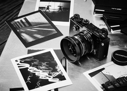 Aparat fotograficzny marki Olympus PEN-F obok czarno-białych zdjęć