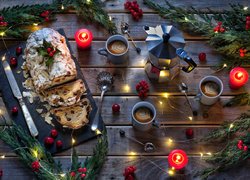 Babka z bakaliami i kubki z kawą obok świątecznej dekoracji i świec