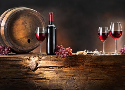 Beczka, butelka i kieliszki z winem oraz kiście winogron na drewnianym blacie