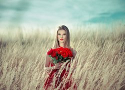 Blondynka w czerwonej sukience i bukietem róż
