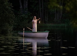 Blondynka z lampą naftową w ręku stoi w łódce