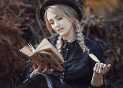 Blondynka z warkoczami czyta książkę