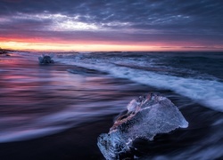 Bryły lodu na morskiej plaży o zachodzie słońca