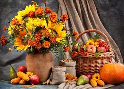 Bukiet jesiennych kwiatów obok koszyka z jabłkami i warzyw