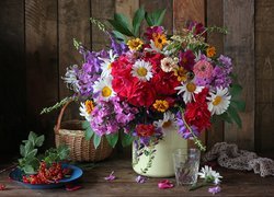 Bukiet różnych kwiatów obok porzeczek i koszyka