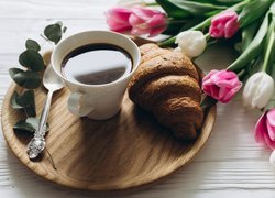 Bukiet tulipanów przy filiżance kawy i croissancie