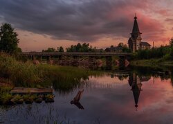 Cerkiew i drzewa nad rzeką o zachodzie słońca