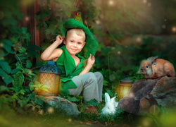 Chłopiec z lampionem i królikami pośród roślinności