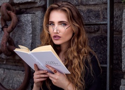 Długowłosa dziewczyna w okularach z książką w dłoniach