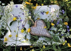 Drewniane serce z kwiatami na książce