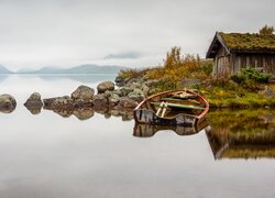 Drewniany dom i łódka na skalistym brzegu jeziora Mosvatnet