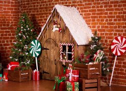 Drewniany domek obok choinek i prezentów w świątecznej dekoracji