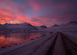 Droga w zimowych górach przy jeziorze o zachodzie słońca
