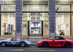 Dwa samochody Porsche przed salonem samochodowym