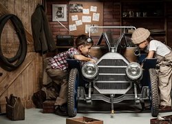 Dwaj chłopcy majsterkują przy zabytkowym samochodzie w garażu