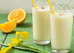 Dwie szklanki mleka obok pomarańczy i irysa