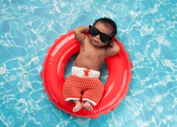 Dziecko w okularach przeciwsłonecznych na kole w basenie