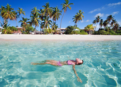 Dziewczyna na wakacjach kąpiąca się w morzu przy plaży z palmami