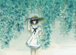 Dziewczyna w kapeluszu pod gałązkami z liśćmi
