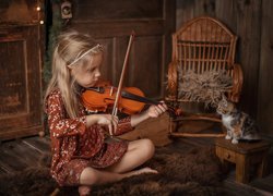 Dziewczynka grająca kotkowi na skrzypcach