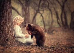 Dziewczynka i niedźwiadek brunatny delektują się owocami leśnymi