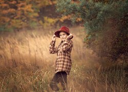 Dziewczynka w czerwonym kapeluszu pod drzewem na polanie