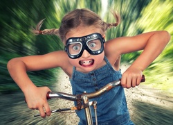 Dziewczynka w goglach mknie na rowerze