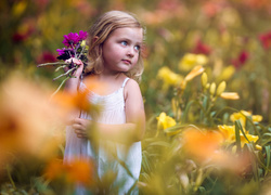 Dziewczynka z bukietem kwiatów na kwiecistej łące