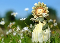 Figurka ustawiona wśród kwiatów na łące
