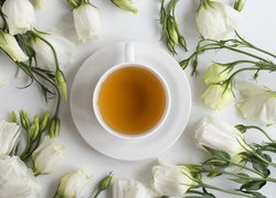 Filiżanka herbaty wśród białych kwiatów eustomy