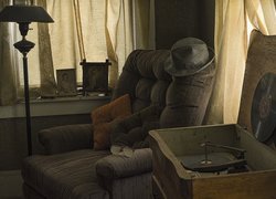 Gramofon obok fotela w zaniedbanym pokoju