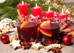 Grzane wino w szklankach i świece w świątecznej kompozycji na stole