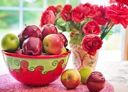 Jabłka w misce obok bukietu kwiatów