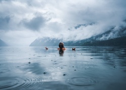 Kąpiel kobiety w górskim jeziorze podczas deszczu