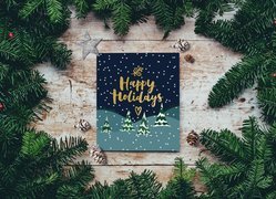 Kartka z napisem Happy Holidays pośród zielonych gałązek