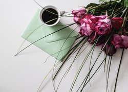 Kawa obok bukietu róż