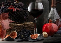 Kieliszek czerwonego wina obok winogron i jesiennych liści