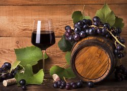 Kieliszek wina obok beczki i winogron