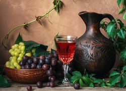 Kieliszek wina obok dzbanka i winogron w misce