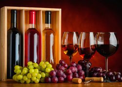 Kiście winogron obok butelek i kieliszków z winem