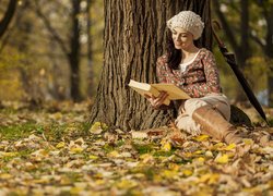 Kobieta czytająca książkę pod drzewem