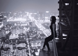 Kobieta na skraju budynku ponad miastem