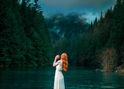 Kobieta nad rzeką spoglądająca na las