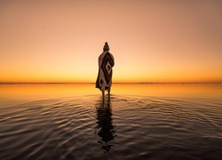 Kobieta nad zatoką w złocistym świetle zachodzącego słońca